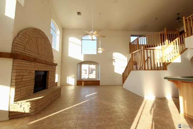 1565 W Vicky Ln, Yuma, AZ 85364 - unfurnished living room with ceiling fan, a fireplace with raised hearth, a towering ceiling, visible vents, and stairway