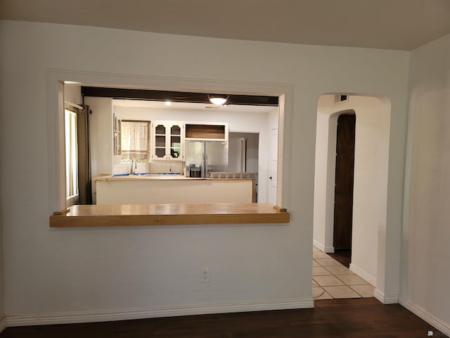 1995 S 10th Ave, Yuma, AZ 85364 - kitchen with stainless steel fridge, arched walkways, a peninsula, baseboards, and wood finished floors