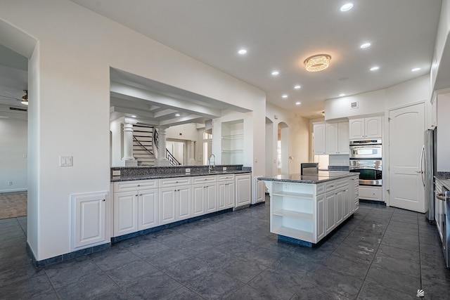 kitchen featuring white cabinets, open shelves, stainless steel double oven, dark stone counters, and recessed lighting
