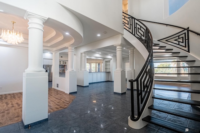 entrance foyer featuring stairway, decorative columns, and a towering ceiling