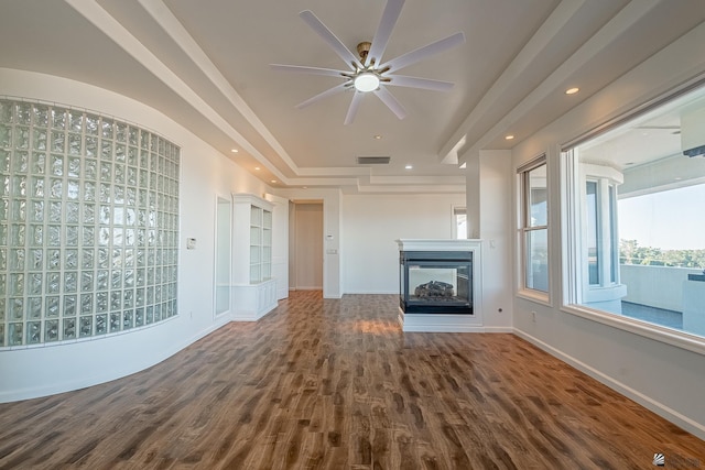 unfurnished living room with a multi sided fireplace, a ceiling fan, visible vents, wood finished floors, and baseboards