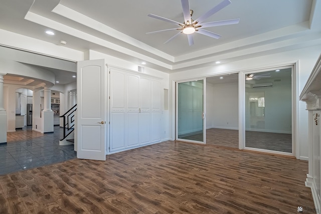 unfurnished bedroom featuring decorative columns, dark wood finished floors, a raised ceiling, multiple closets, and recessed lighting