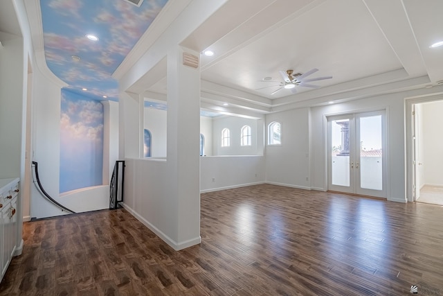 interior space featuring dark wood-style flooring, ceiling fan, baseboards, a tray ceiling, and visible vents