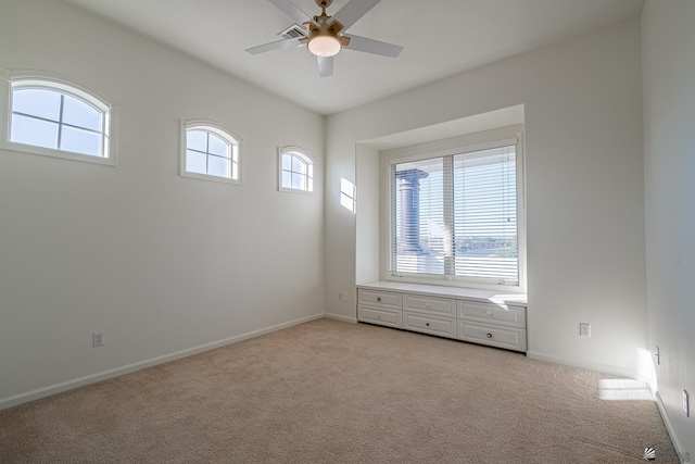 spare room featuring baseboards, light carpet, and a ceiling fan