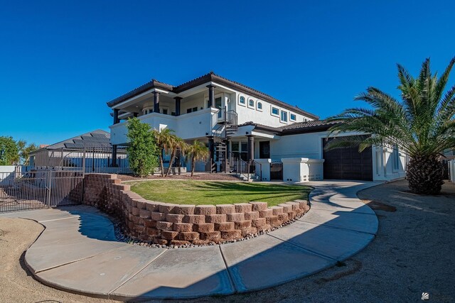 rear view of house featuring a garage, fence, a balcony, stucco siding, and a tile roof