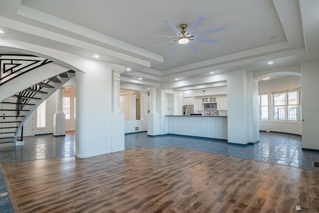 unfurnished living room with dark wood-style flooring, a ceiling fan, baseboards, and a raised ceiling