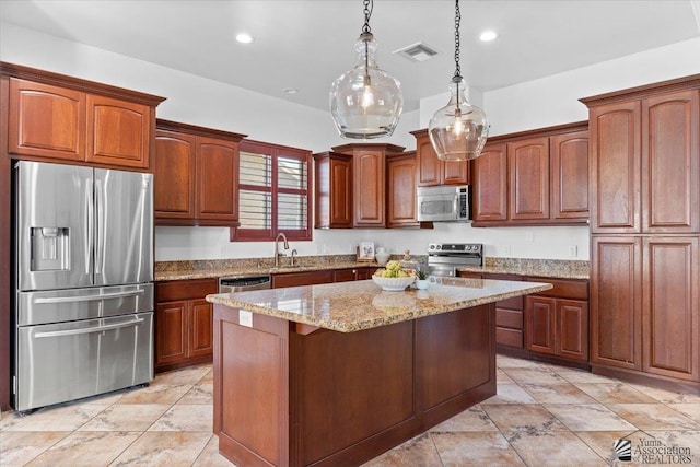 kitchen with appliances with stainless steel finishes, a sink, a center island, light stone countertops, and decorative light fixtures