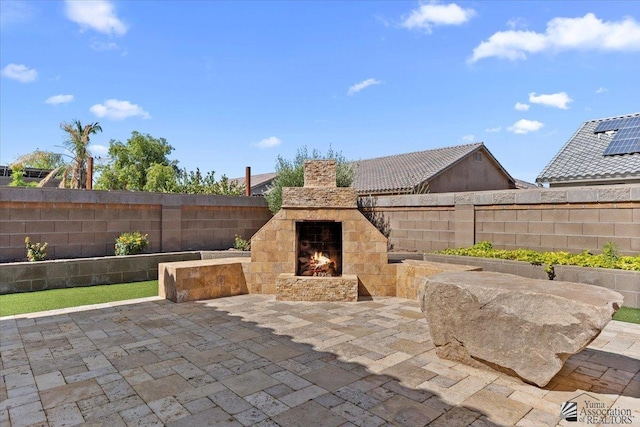 view of patio / terrace with an outdoor stone fireplace and fence