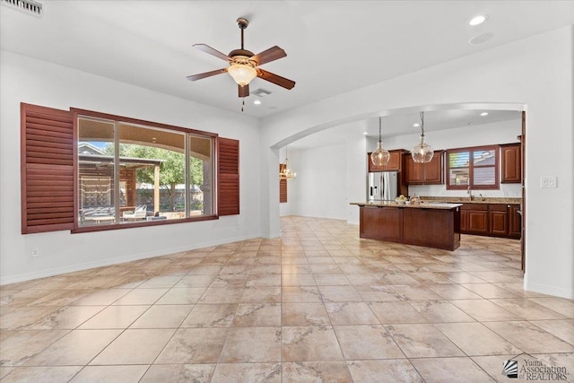 unfurnished living room with arched walkways, a ceiling fan, a sink, recessed lighting, and baseboards