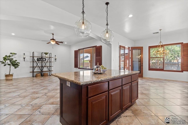 kitchen featuring a center island, decorative light fixtures, recessed lighting, ceiling fan, and light stone countertops