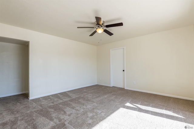unfurnished room with a ceiling fan, baseboards, and carpet