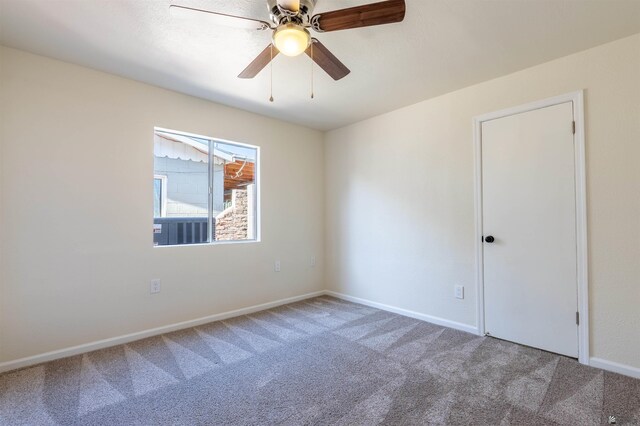 carpeted empty room with baseboards and a ceiling fan