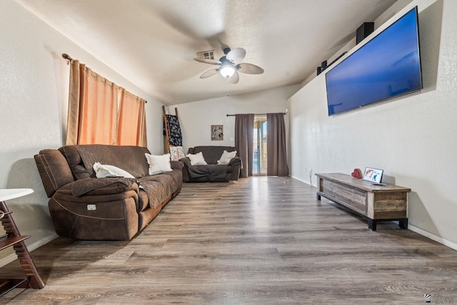 living room featuring ceiling fan, visible vents, vaulted ceiling, wood finished floors, and baseboards
