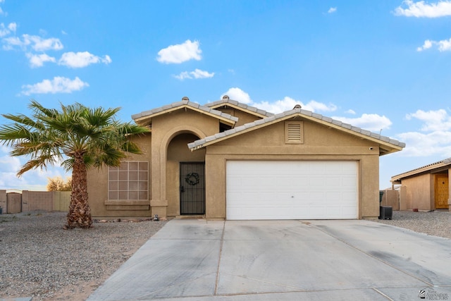 view of front of house with fence, stucco siding, an attached garage, and driveway