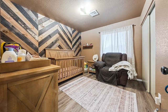 bedroom featuring visible vents, a textured ceiling, and wood finished floors