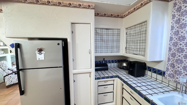 13725 E 46th St, Yuma, AZ 85367 - kitchen with freestanding refrigerator, tile countertops, and white cabinetry