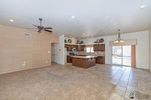 11561 E 25th Pl, Yuma, AZ 85367 - kitchen with open floor plan, a kitchen island, ceiling fan, light countertops, and arched walkways