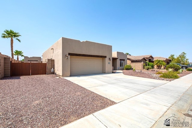 11561 E 25th Pl, Yuma, AZ 85367 - pueblo revival-style home with a garage, driveway, stucco siding, and a gate