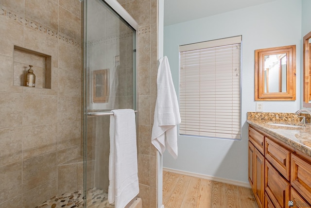 full bathroom with baseboards, a shower stall, wood finished floors, and vanity