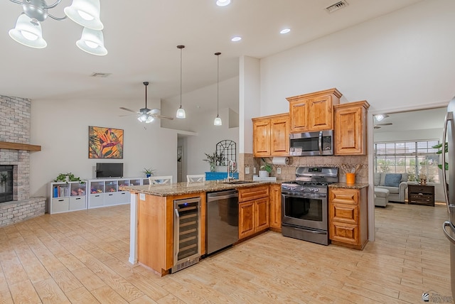 kitchen featuring ceiling fan, appliances with stainless steel finishes, a sink, beverage cooler, and open floor plan