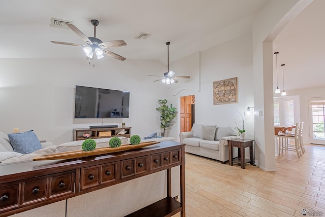 living room with visible vents, a ceiling fan, light wood-style floors, and high vaulted ceiling