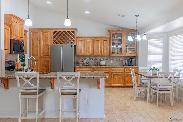kitchen with freestanding refrigerator, vaulted ceiling, decorative backsplash, and visible vents