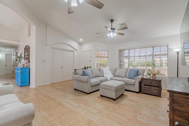 living area with visible vents, lofted ceiling, ceiling fan, arched walkways, and light wood-style flooring