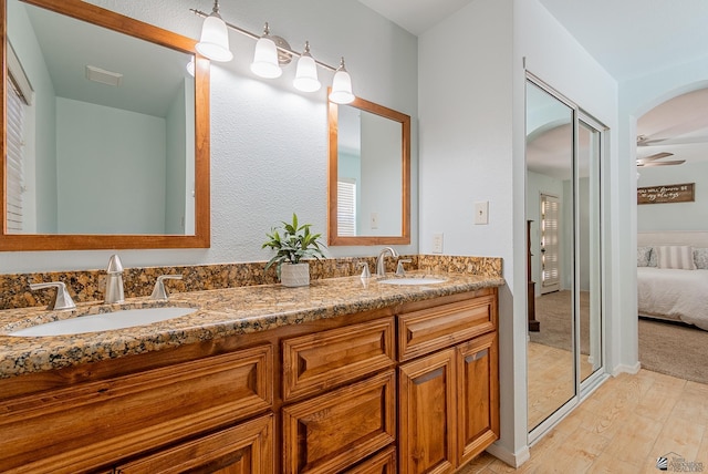 bathroom featuring connected bathroom, a ceiling fan, a sink, and wood finished floors
