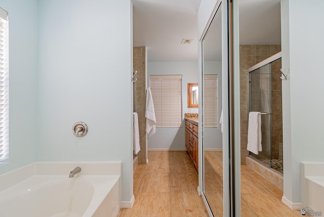full bathroom featuring a garden tub, visible vents, a shower stall, wood finished floors, and vanity