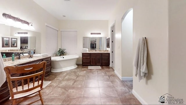 full bathroom featuring tile patterned floors, a freestanding tub, and two vanities