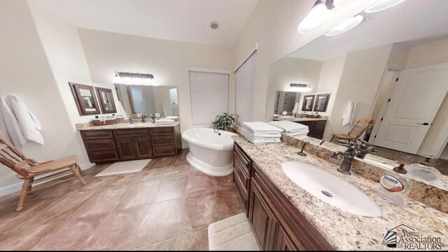 bathroom featuring tile patterned flooring, a sink, a freestanding bath, and two vanities