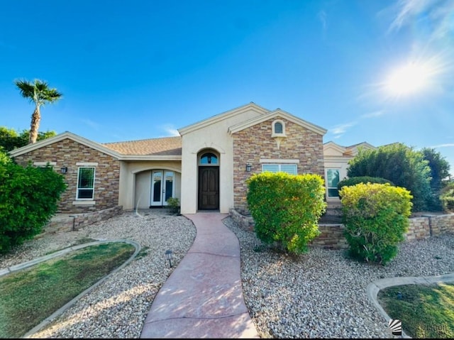 ranch-style house featuring stucco siding, french doors, and stone siding
