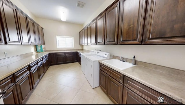 clothes washing area with cabinet space, a sink, light tile patterned floors, visible vents, and washing machine and dryer