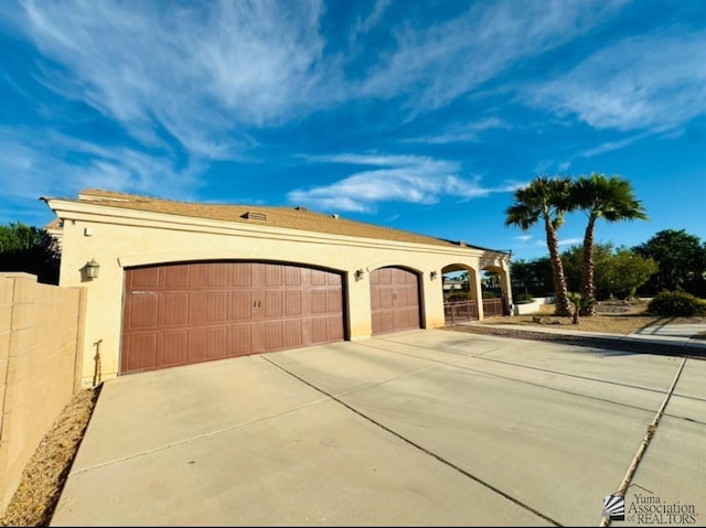 view of front of property featuring a garage, fence, stucco siding, and concrete driveway