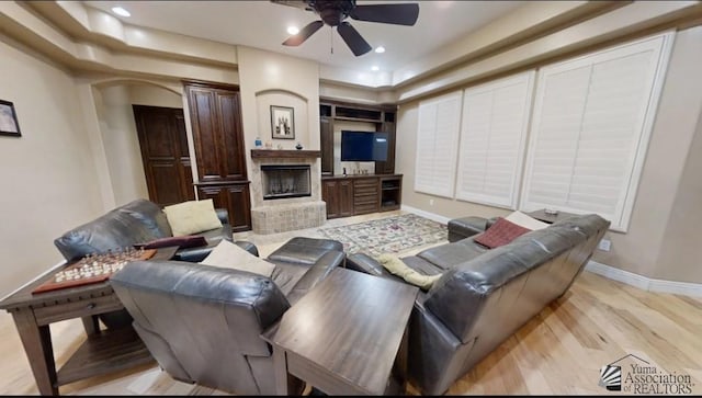 living area featuring light wood-style floors, a fireplace, a ceiling fan, baseboards, and recessed lighting