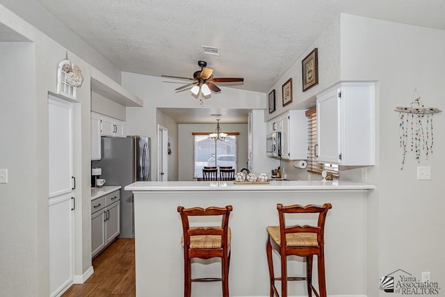 4452 S Agave Ave, Yuma, AZ 85365 - kitchen with a ceiling fan, a textured ceiling, a peninsula, a breakfast bar area, and dark wood-style floors