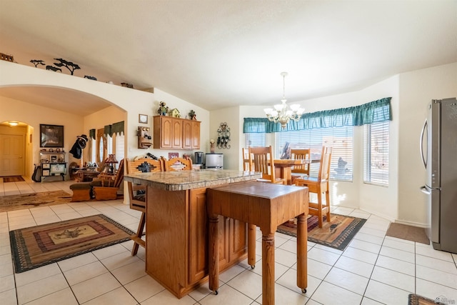 14530 E 55th St, Yuma, AZ 85367 - kitchen featuring brown cabinets, arched walkways, a chandelier, freestanding refrigerator, and light tile patterned floors