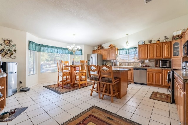 14530 E 55th St, Yuma, AZ 85367 - kitchen featuring appliances with stainless steel finishes, tasteful backsplash, a center island, brown cabinets, and an inviting chandelier