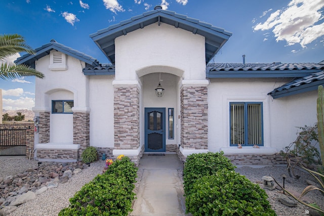 13779 E 54th Dr, Yuma, AZ 85367 - view of exterior entry with a tiled roof, stone siding, and stucco siding