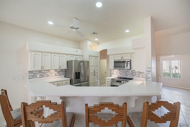 13779 E 54th Dr, Yuma, AZ 85367 - kitchen with ceiling fan, backsplash, stainless steel appliances, and a kitchen bar