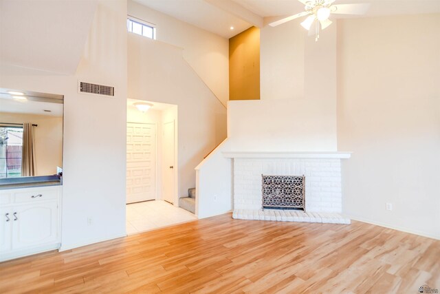 12402 E Via Estrella, Yuma, AZ 85367 - unfurnished living room featuring a ceiling fan, light wood-type flooring, a towering ceiling, stairs, and a fireplace