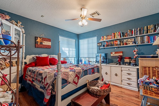 bedroom with ceiling fan, light hardwood / wood-style flooring, and a textured ceiling