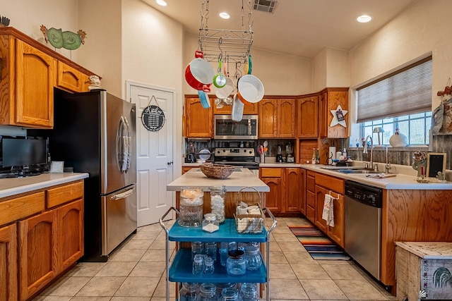 kitchen with light tile patterned flooring, appliances with stainless steel finishes, a center island, and sink