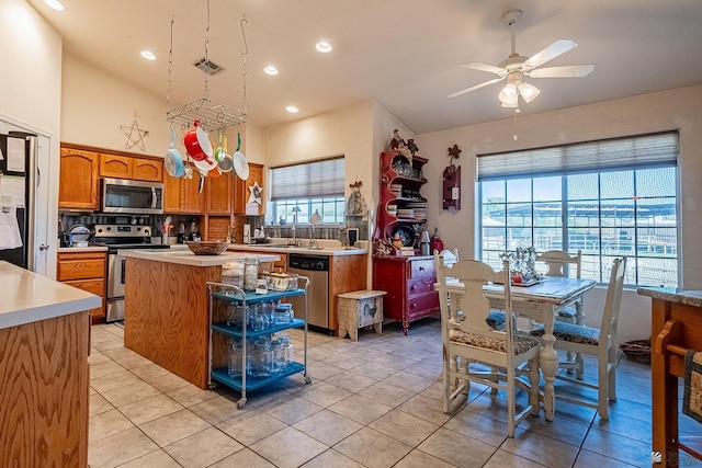 kitchen featuring stainless steel appliances, ceiling fan, sink, light tile patterned floors, and a kitchen island