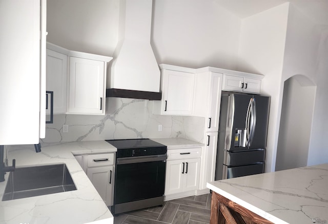 kitchen featuring white cabinetry, stainless steel fridge with ice dispenser, custom exhaust hood, and range with electric cooktop