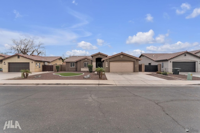 mediterranean / spanish home featuring concrete driveway, a tiled roof, fence, and stucco siding