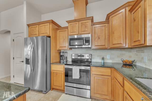 kitchen with tasteful backsplash, appliances with stainless steel finishes, and dark stone counters