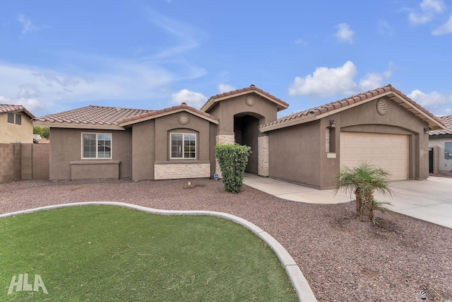 mediterranean / spanish-style home featuring fence, an attached garage, stucco siding, concrete driveway, and a tiled roof