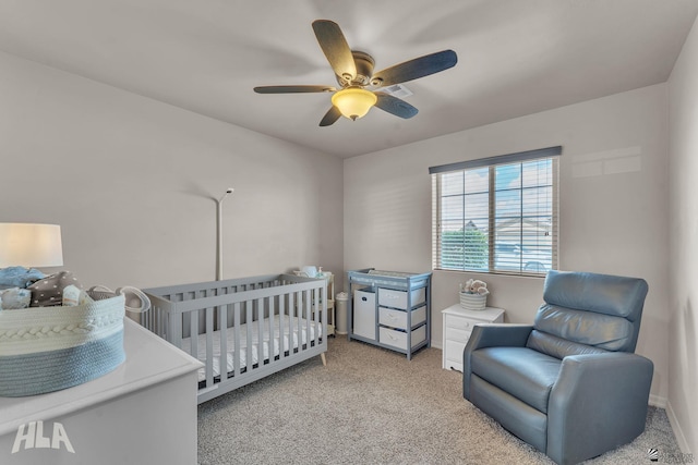 bedroom with a ceiling fan, a nursery area, carpet, and baseboards