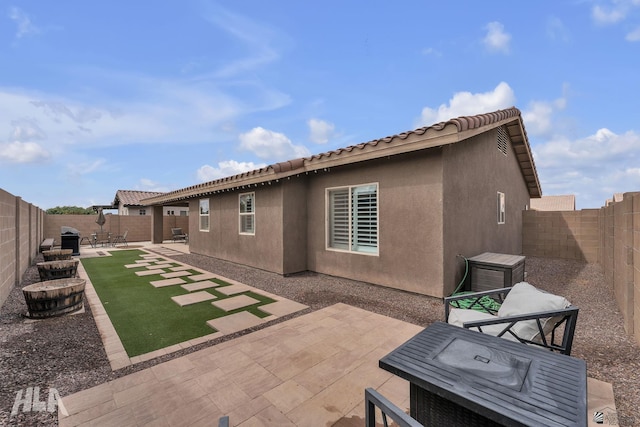 back of property with a fenced backyard, stucco siding, a tiled roof, and a patio